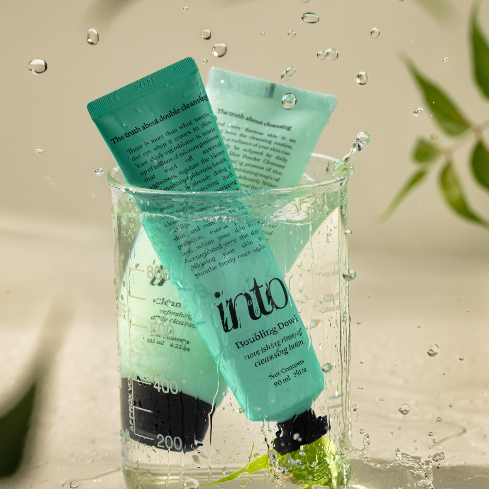 Cleanser and cleansing balm immersed in a glass of water, highlighting their hydrating and gentle formulation. Perfect for refreshing and deep cleansing skincare routines.