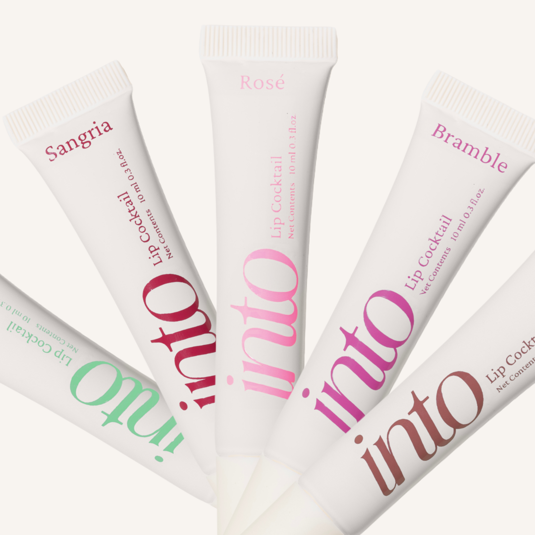 Multiple tubes of INTO lip cocktail with different flavors on a white background