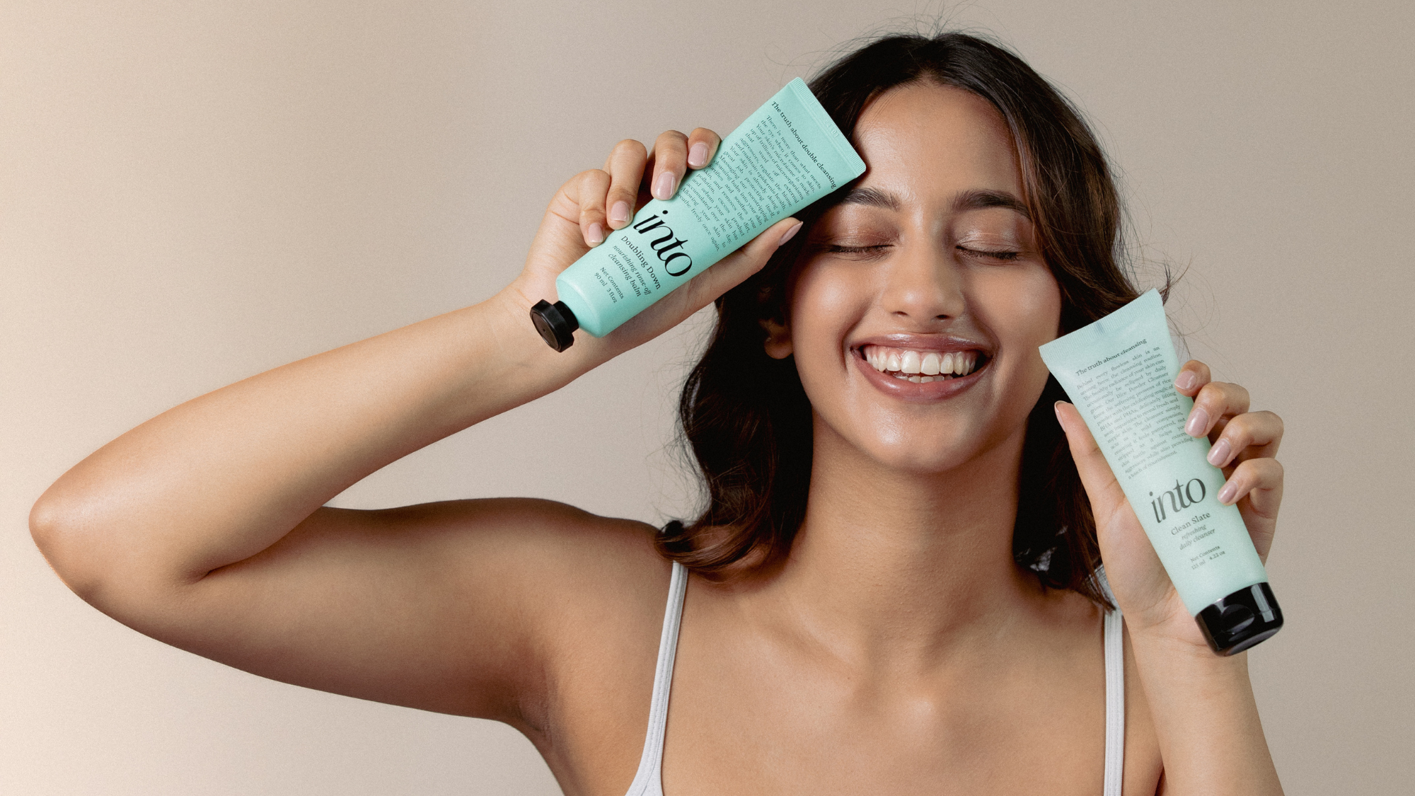 Model holding a cleansing balm and cleanser in each hand, showcasing skincare products for a double-cleansing routine. Ideal for clear, healthy skin, these products combine effectiveness with gentle care.